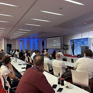 Teilnehmer im Konferenzsaal der Automotive Lighting Conference 2026, Stephan Berlitz im Hintergrund auf der Bühne