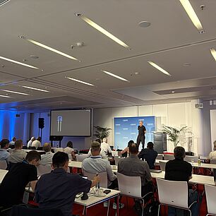 Michael Bantel auf der Bühne bei der Automotive Lighting Conference 2026 im Hintergrund, Teilnehmersaal im Vordergrund